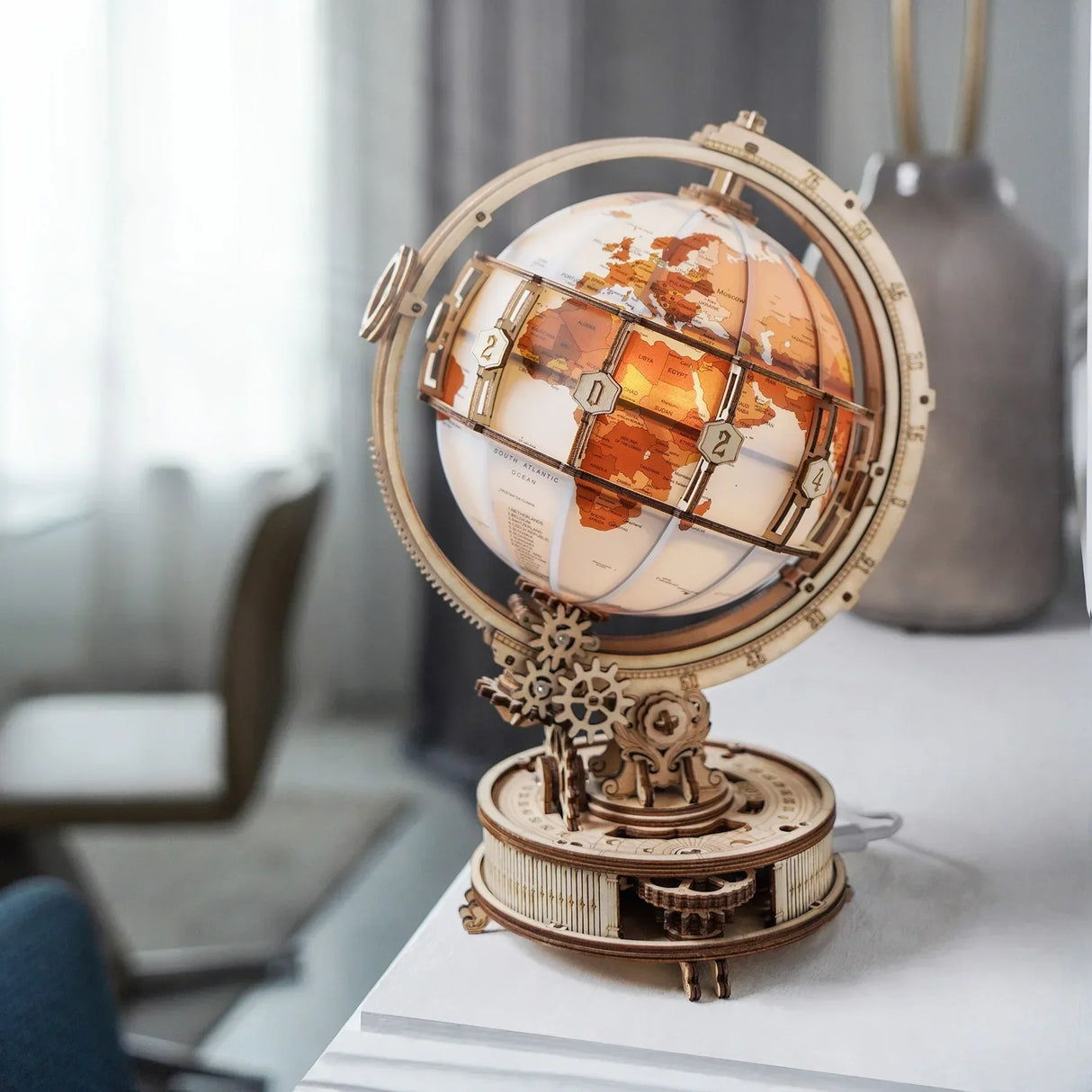 Ein beleuchteter Holzglobus mit Zahnrädern und Weltkarte auf einem Tisch