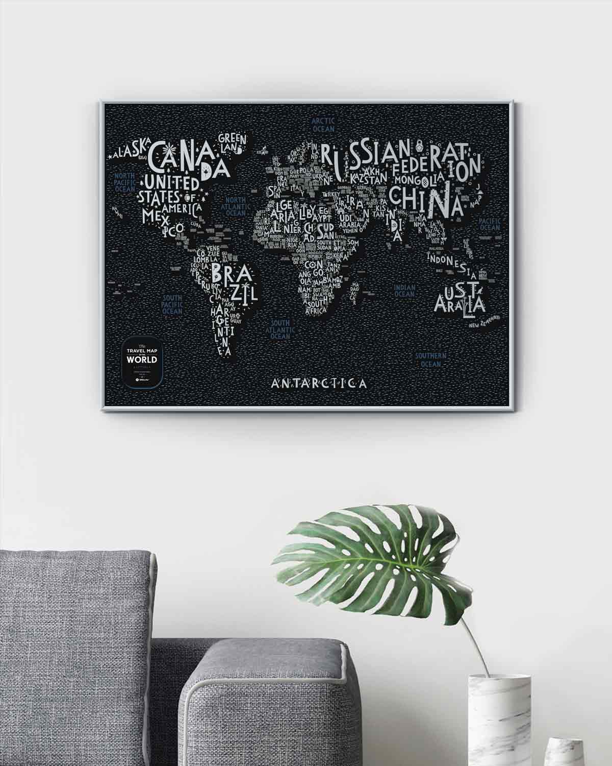 Wandbild mit einer Weltkarte aus Ländernamen auf schwarzem Hintergrund über einem grauen Sofa