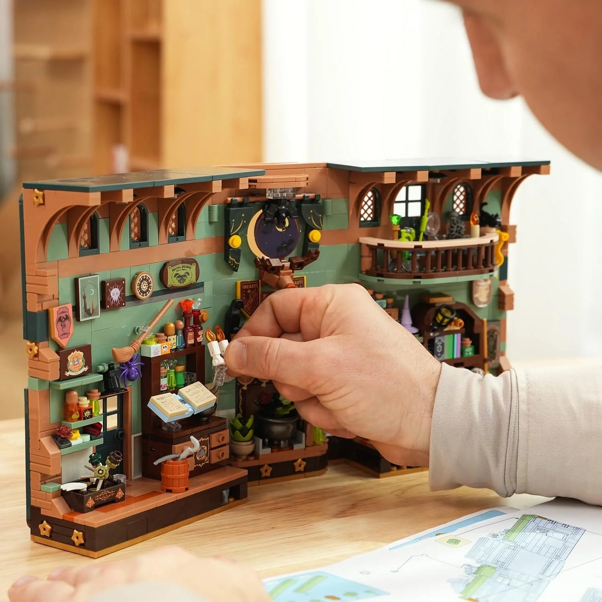 Person baut ein detailliertes LEGO-Modell eines magischen Ladens mit Tränken und Büchern