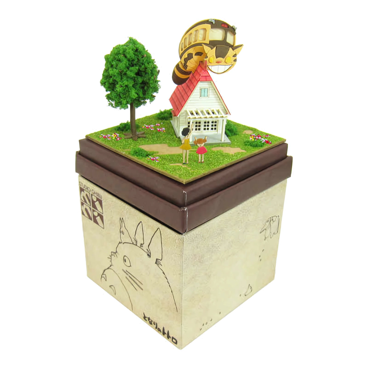 Diorama mit Haus, Baum, zwei Figuren und Catbus auf dem Dach, auf einer Box mit Totoro-Zeichnung