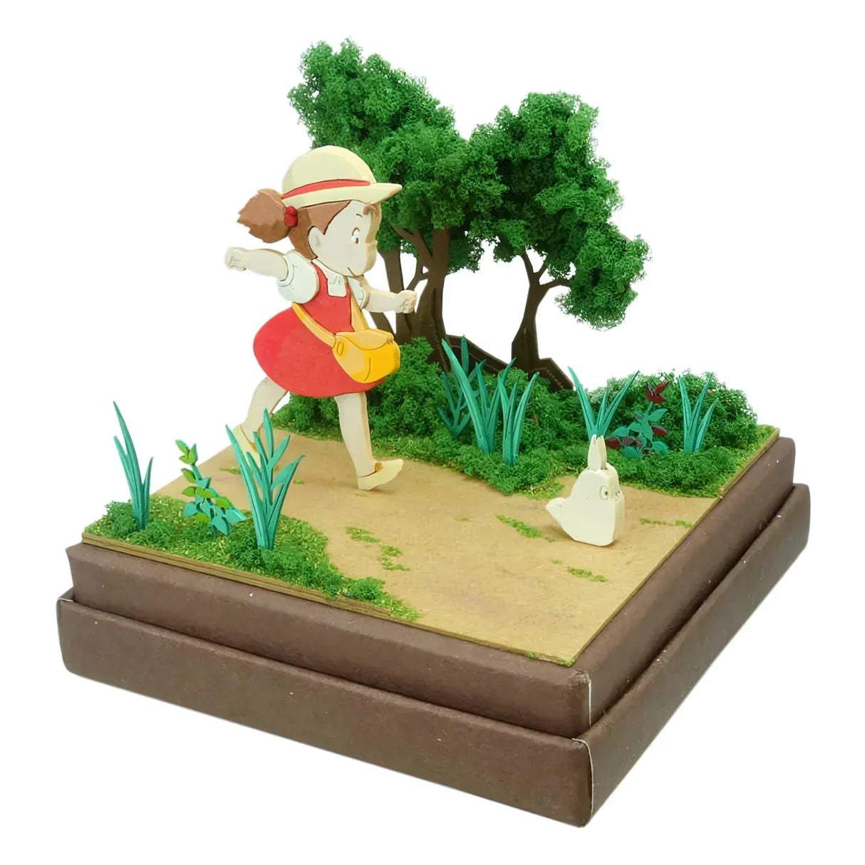 Diorama mit Mädchen in rotem Kleid und Strohhut, das auf einem Weg geht, gefolgt von einem kleinen weißen Totoro