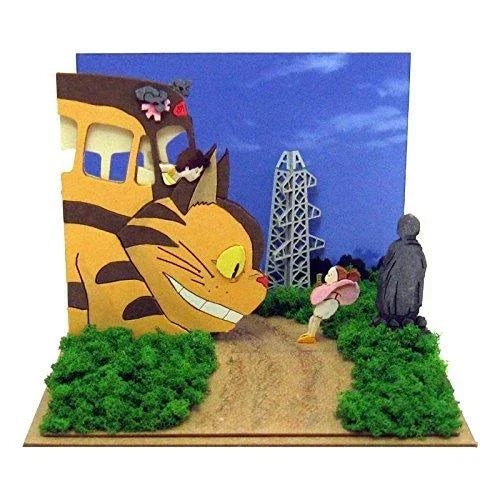 Diorama mit Catbus, Mädchen und Totoro-Figur auf einem Pfad mit Büschen und blauem Himmel