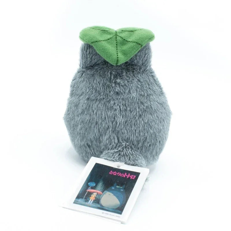 Graues Totoro Plüschtier mit grünem Blatt auf dem Kopf und Etikett
