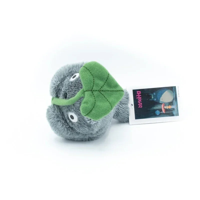 Graues Totoro Plüschtier mit grünem Blatt auf dem Kopf und Etikett
