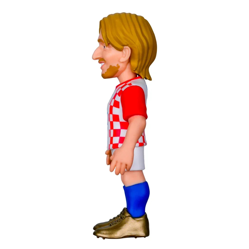 Seitenansicht einer Karikaturfigur eines Fussballspielers mit blonden Haaren und Bart in rot-weiss kariertem Trikot