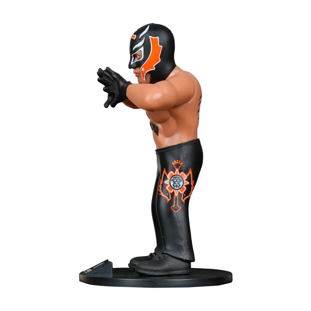 Rey Mysterio Figur mit schwarzer Maske und Hose, orangefarbenen Details, auf schwarzem Sockel