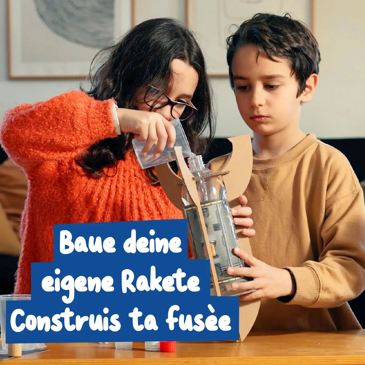Zwei Kinder bauen eine Rakete aus einer Plastikflasche und Pappe