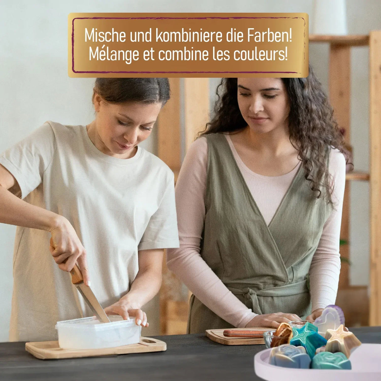 Zwei Frauen stellen Seifen her, eine schneidet Seifenbasis, die andere schaut zu, fertige Seifenformen im Vordergrund
