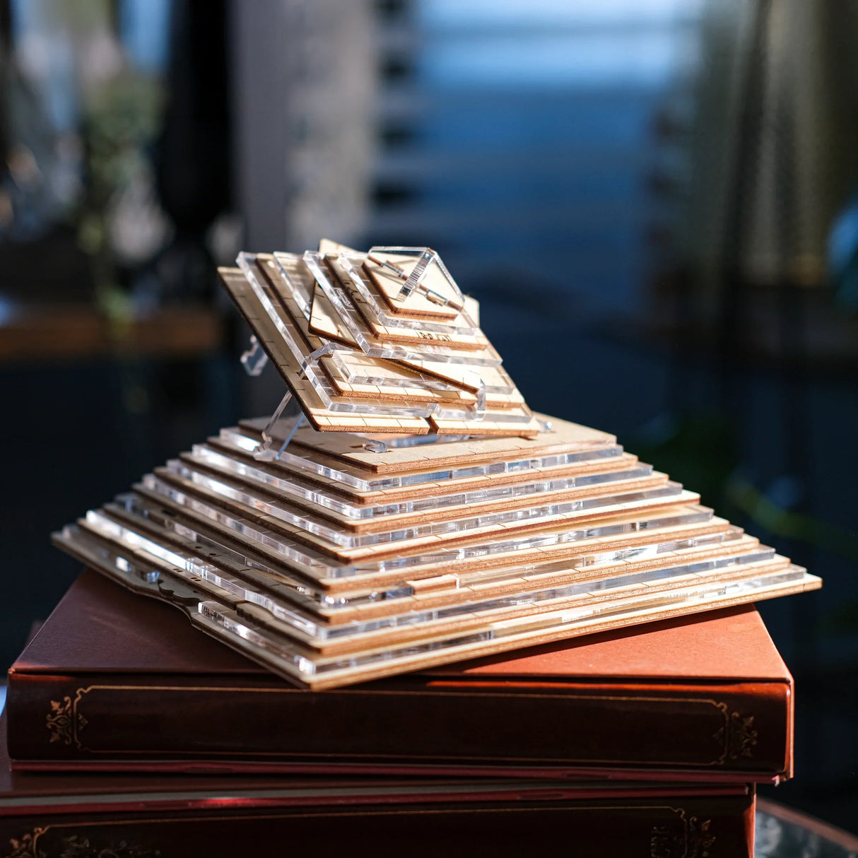Holz- und Acrylpyramide auf einem Stapel brauner Bücher