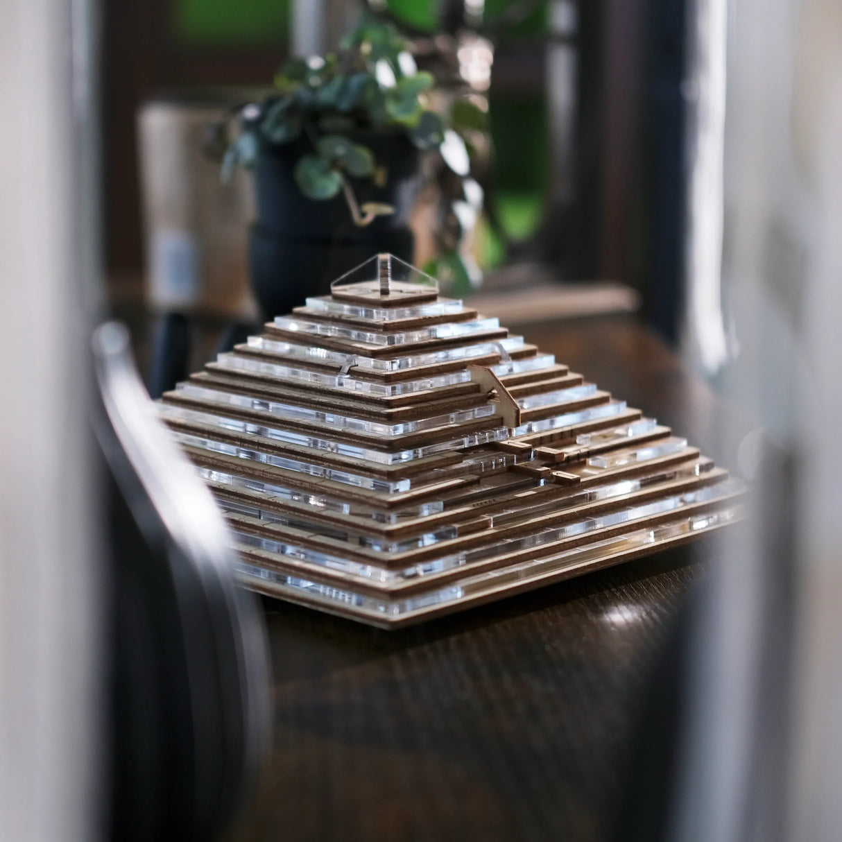 Holzpyramide mit transparenten Acrylplatten auf einem dunklen Holztisch
