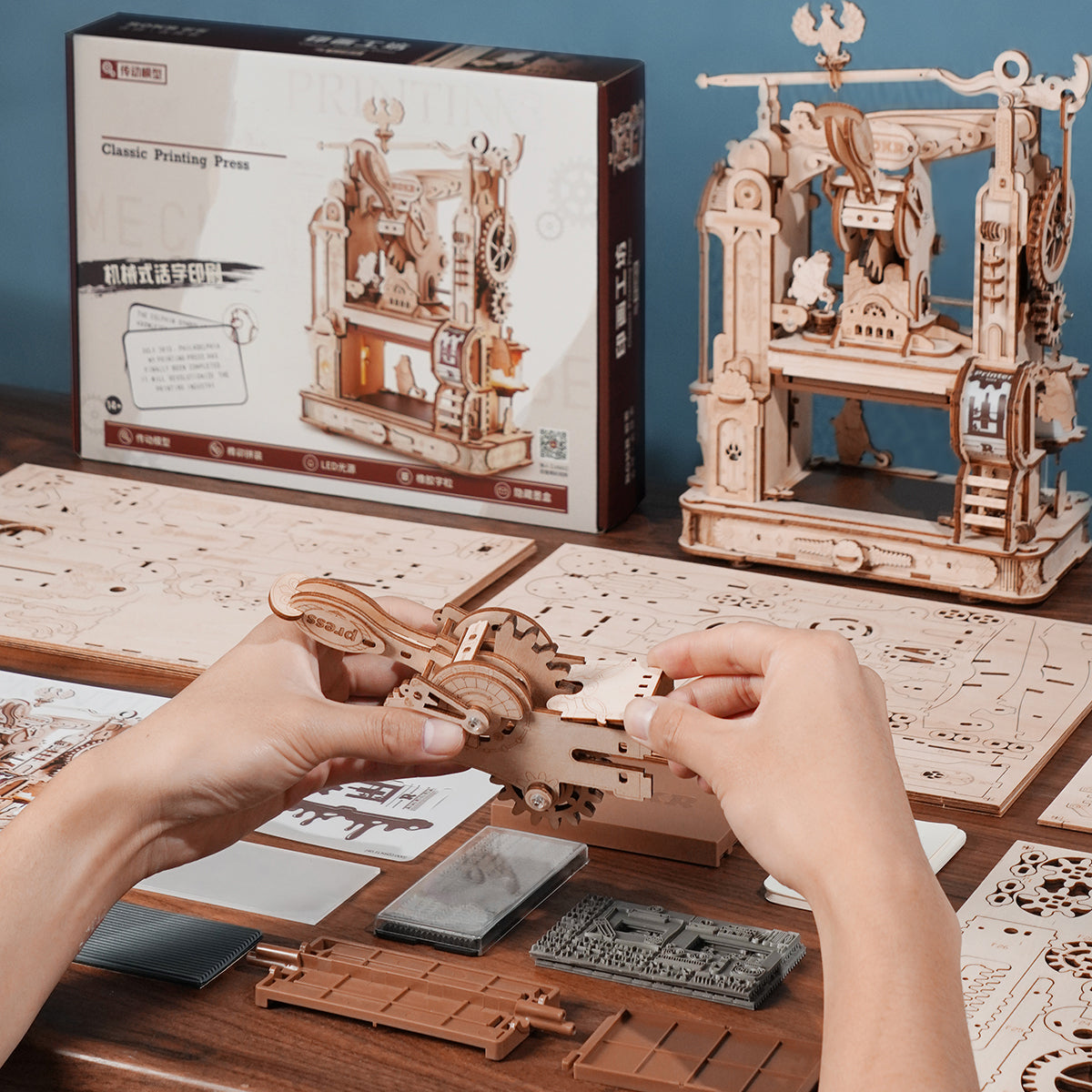 Hände beim Zusammenbau eines mechanischen Holzmodellbausatzes einer historischen Druckerpresse