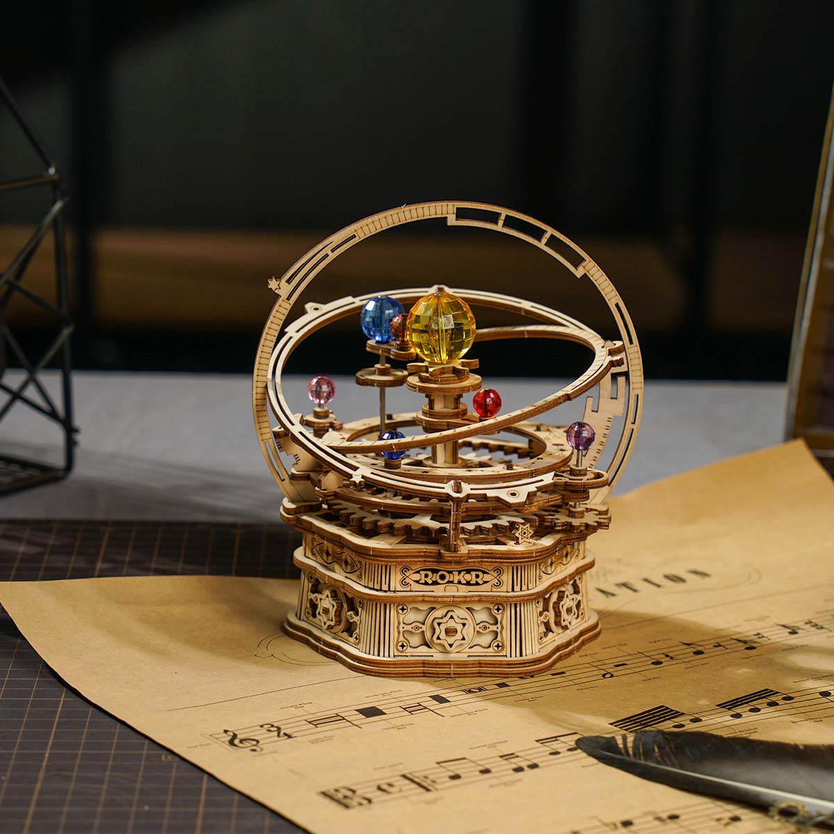 Mechanisches Holzmodell eines Planetariums mit bunten Glaskugeln auf einem Notenblatt