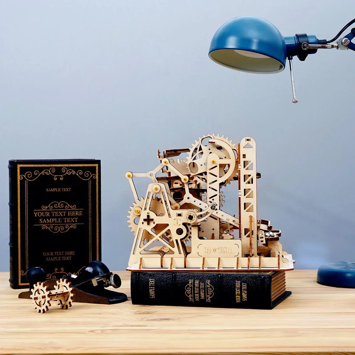 Mechanisches Holzmodell einer Kugelbahn auf einem Buch stehend neben einer Schreibtischlampe
