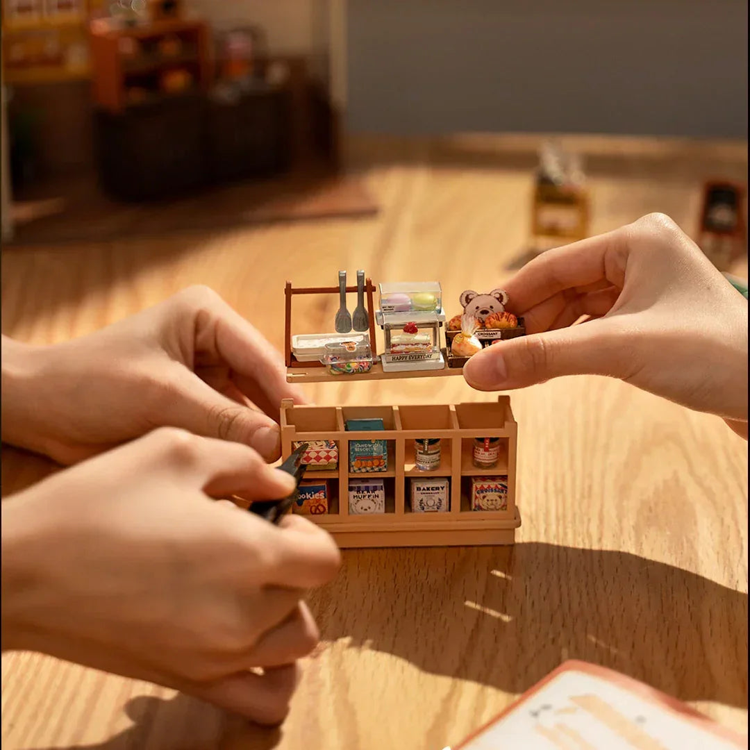 Hände setzen Miniatur Bäckereiregal zusammen