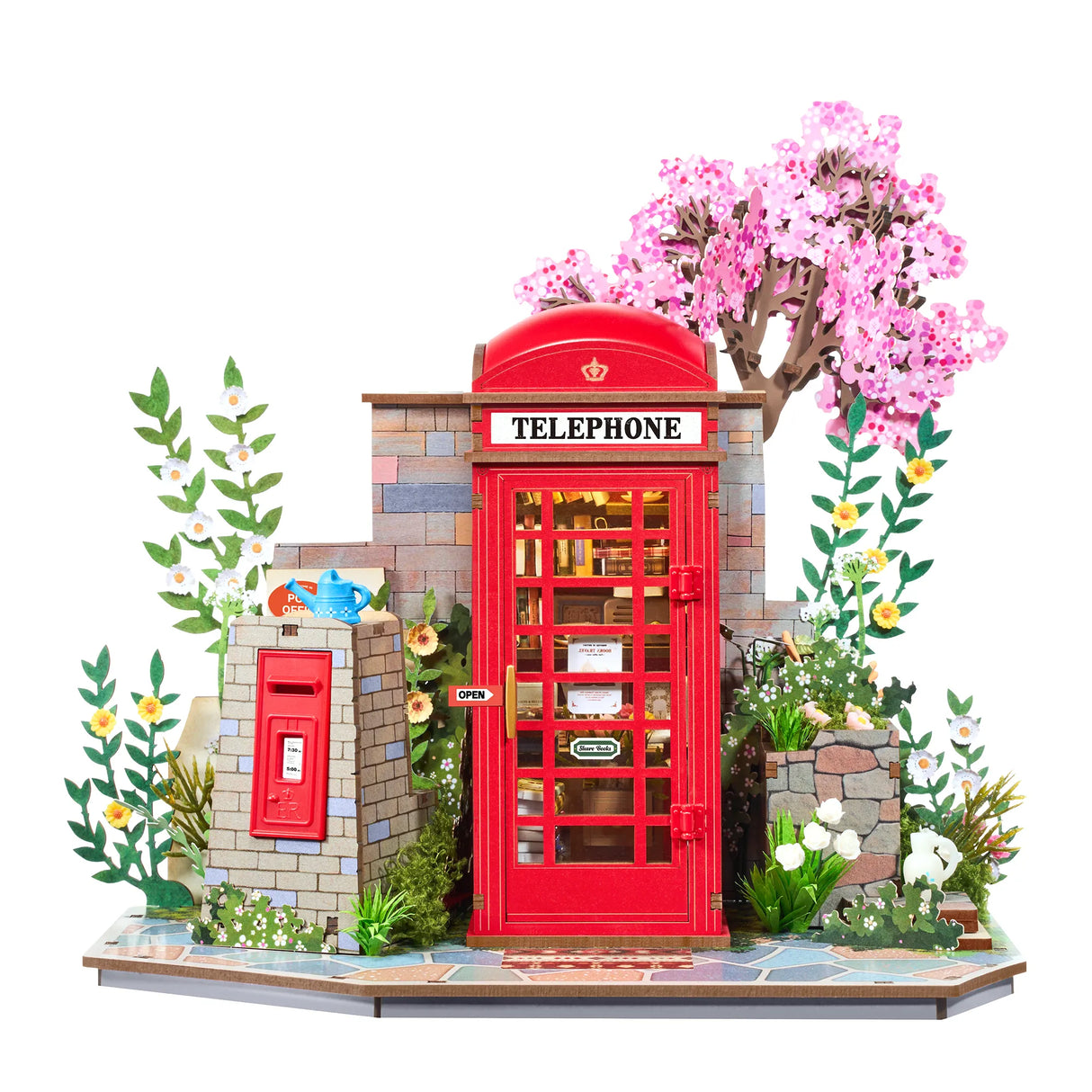 Miniatur-Telefonzelle mit Briefkasten und blühenden Bäumen