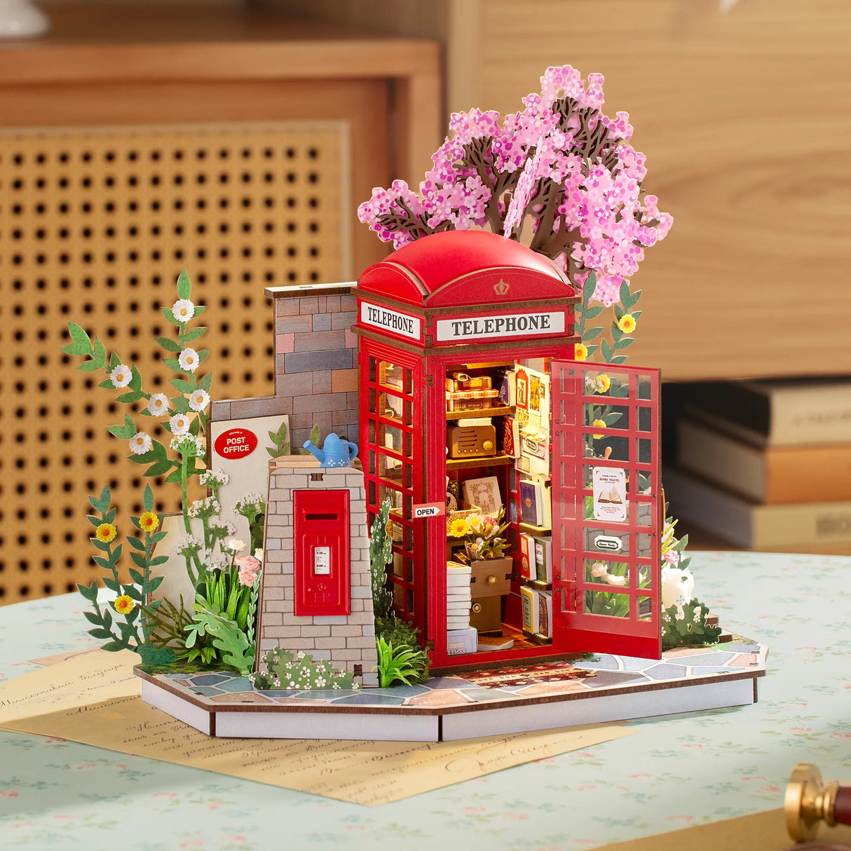 Miniatur-Diorama mit roter Telefonzelle, Postamt und blühenden Bäumen