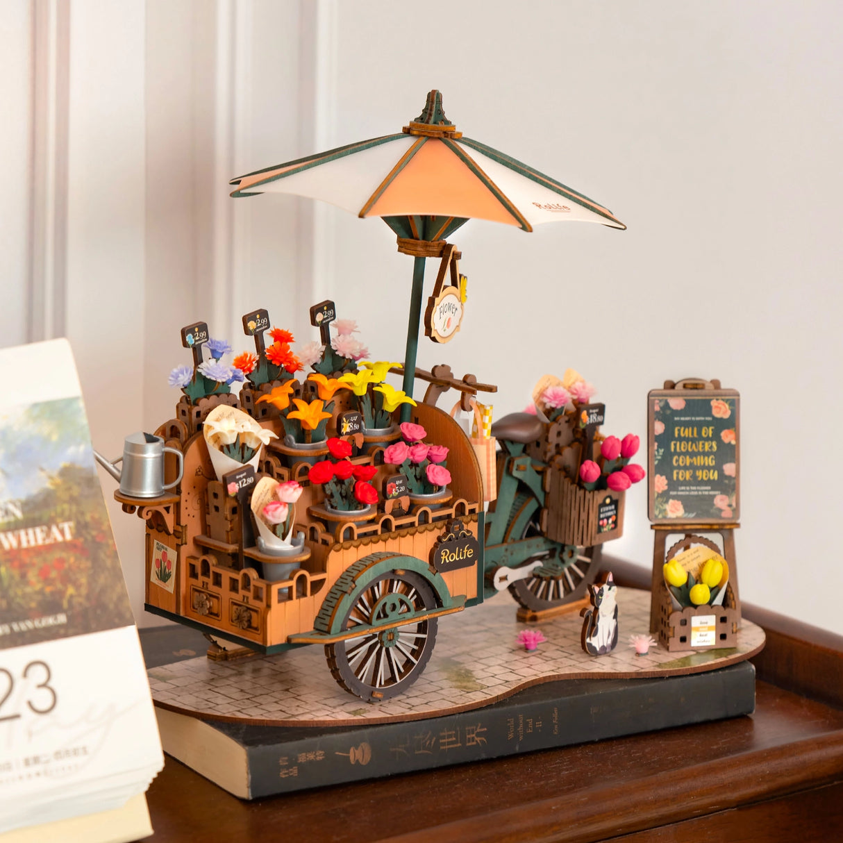 Miniatur-Blumenstand auf Rädern mit Sonnenschirm, gefüllt mit bunten Blumen und Preisschildern