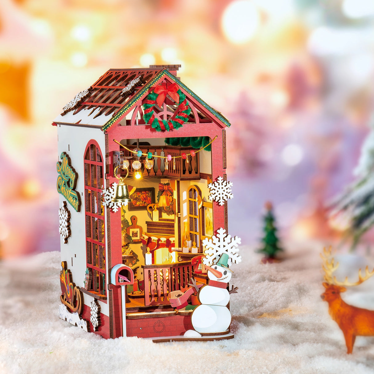 Miniatur-Weihnachtshaus mit Schneemann und Rentier im Schnee