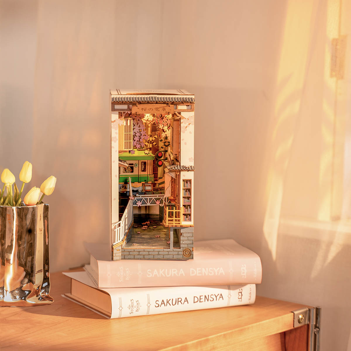 Beleuchtetes Buchstützen Diorama mit japanischer Straßenbahn und Kirschblüten auf zwei Büchern