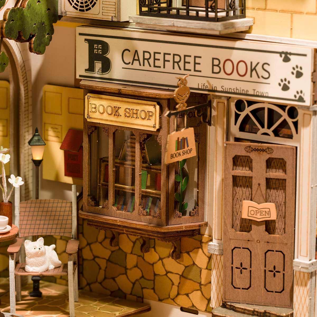 Miniatur Buchladen aus Holz mit Schild Carefree Books und kleiner Katzenfigur auf einem Stuhl
