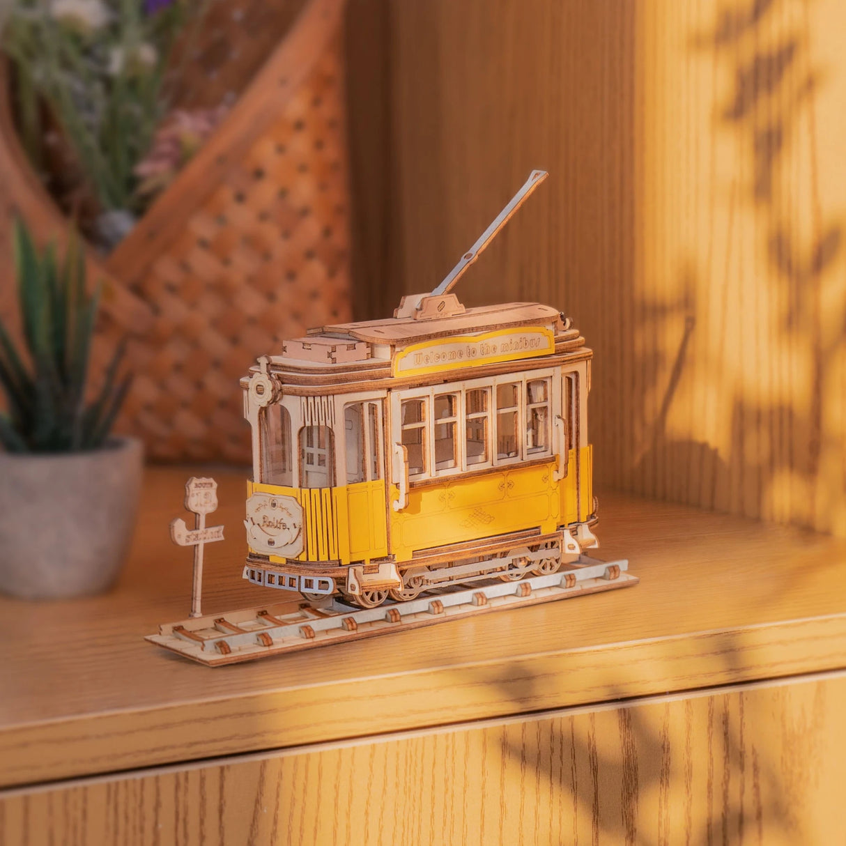 Modell einer gelben Straßenbahn aus Holz auf Schienen