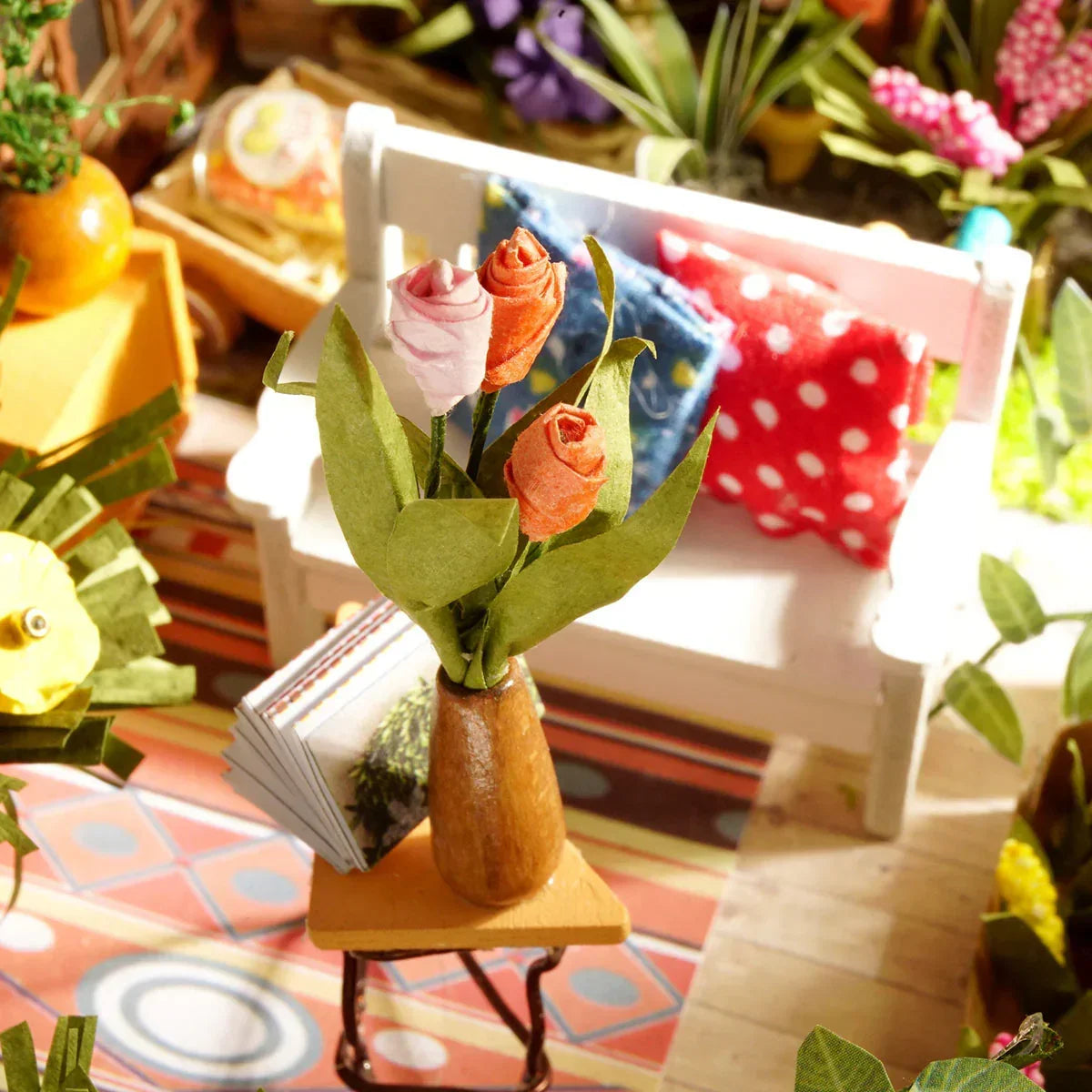 Miniaturvase mit drei Stoffblumen auf einem kleinen Tisch vor einer weißen Bank