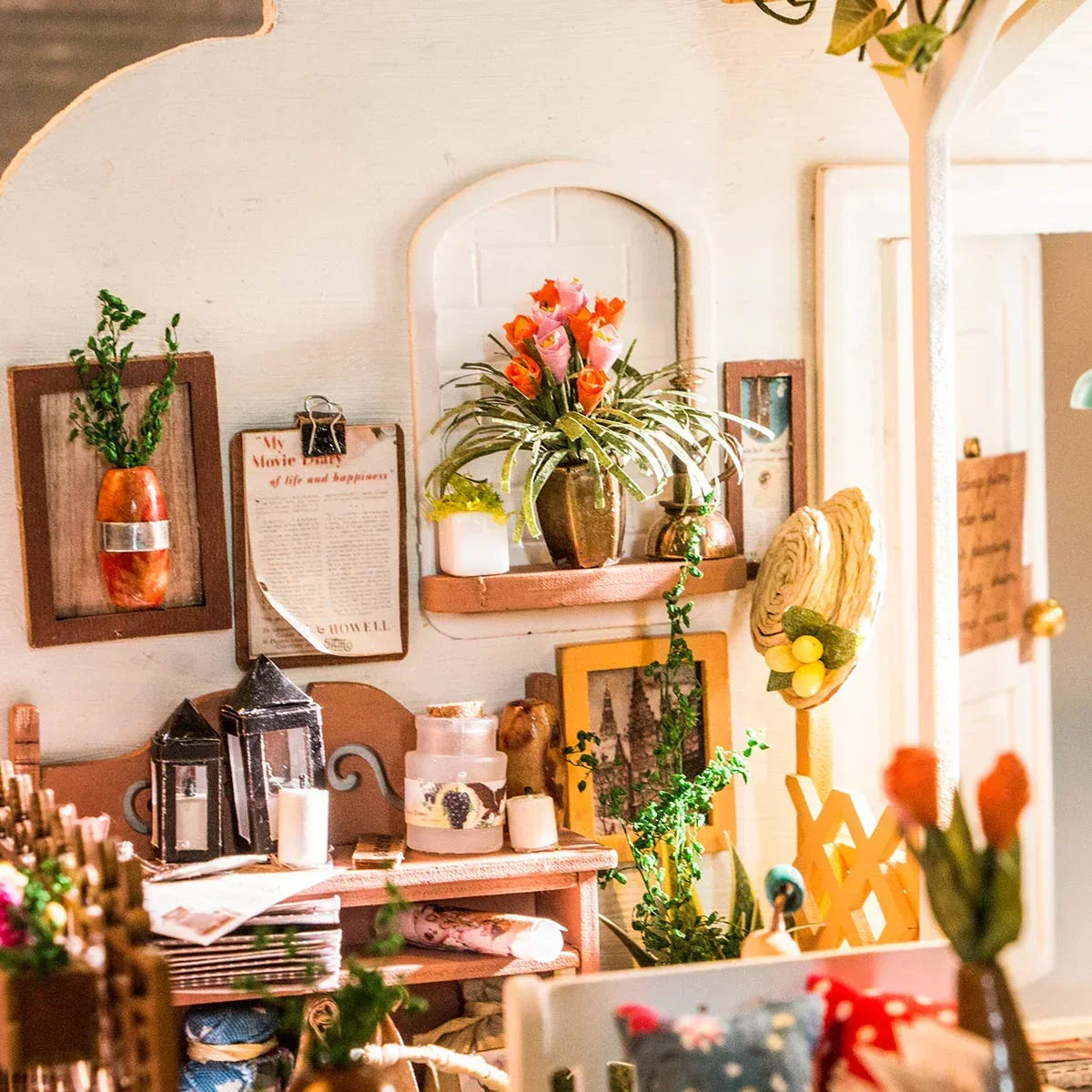 Miniatur Interieur mit Wanddekoration Blumen in Vasen und kleinen Laternen auf einem Tisch