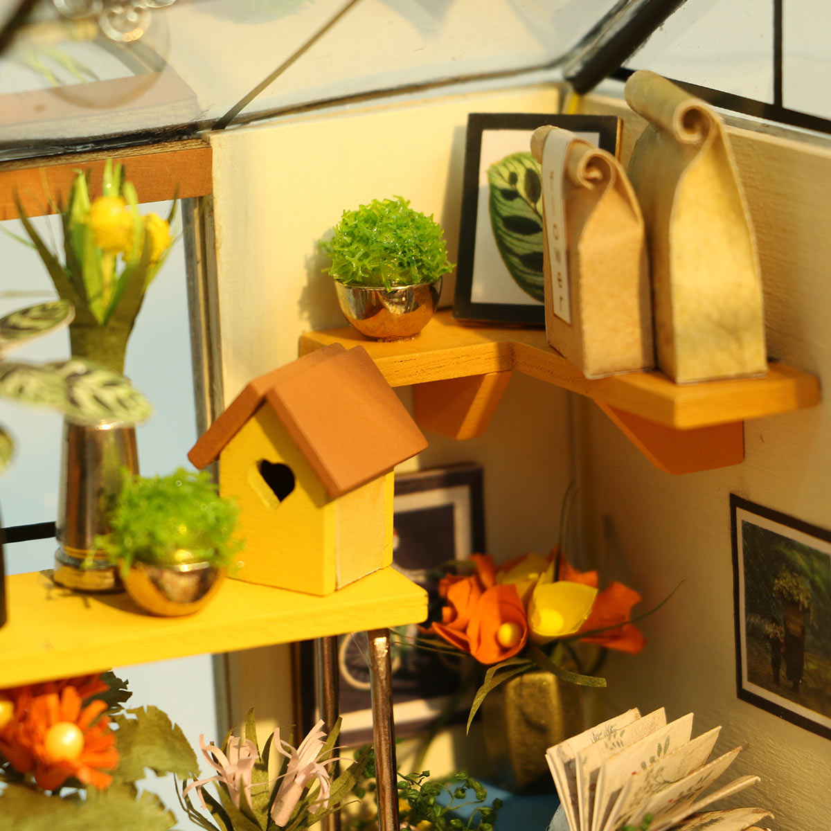 Miniaturregal mit gelbem Vogelhaus Pflanzen und Dekoration in einem Gewächshausmodell