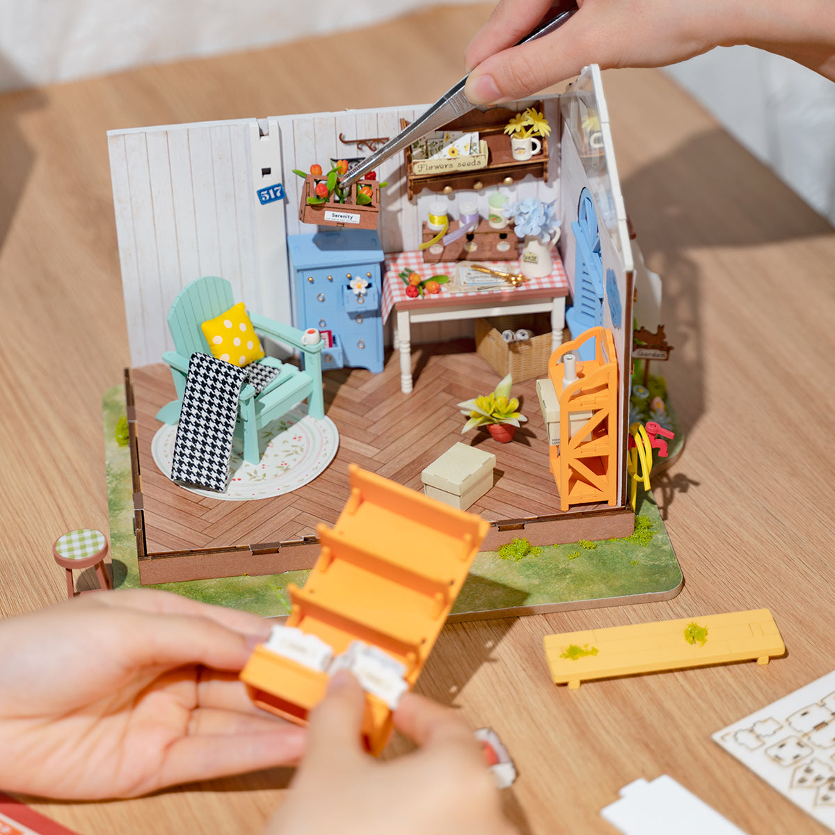 Person baut ein Miniatur Gartenhaus Modell mit Pinzette zusammen
