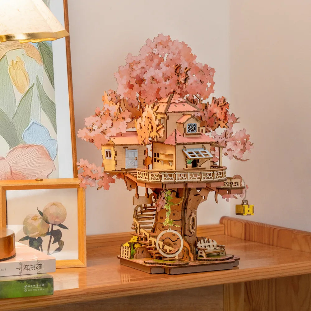 Baumhaus-Modell aus Holz mit rosa Blättern auf einem Holztisch