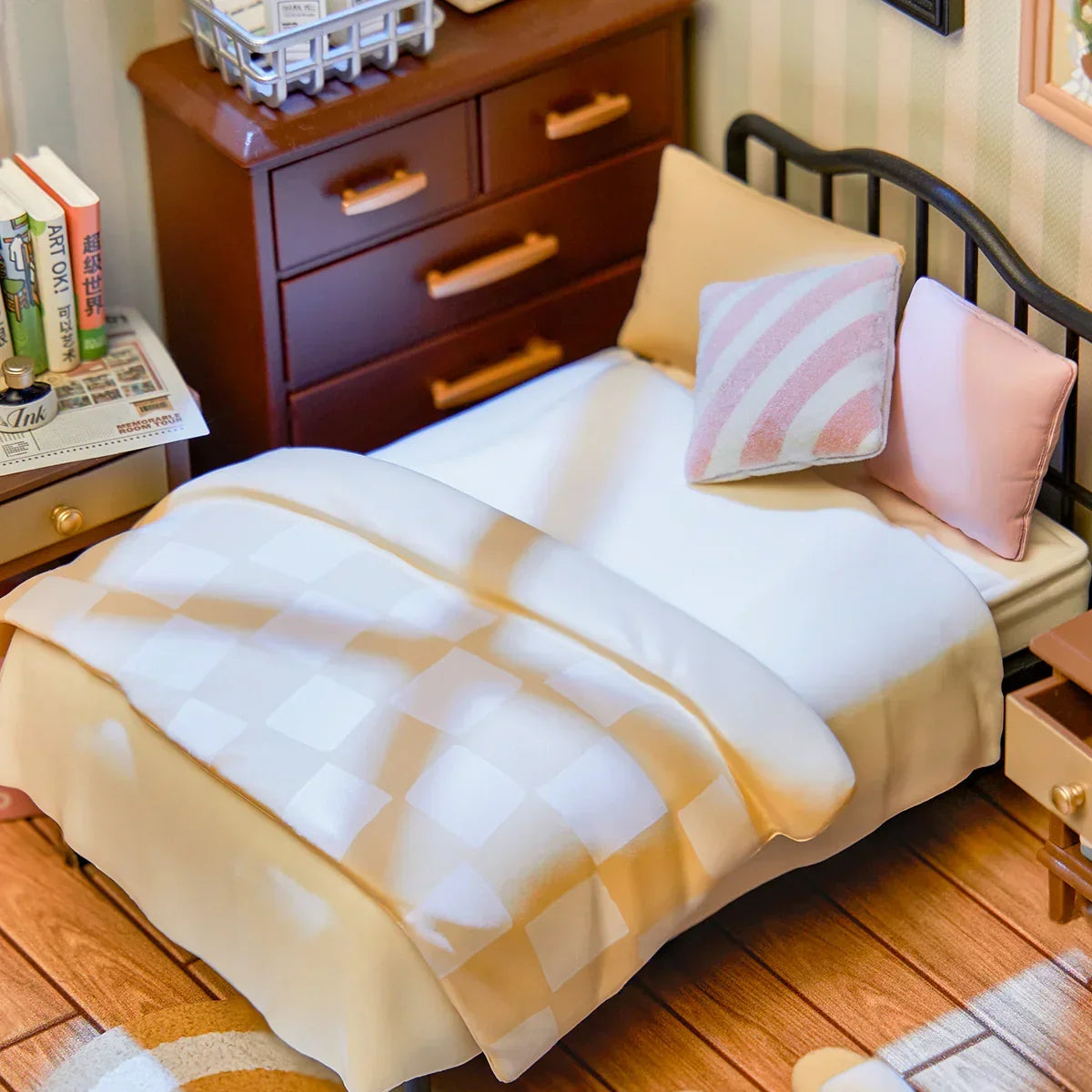 Miniaturbett mit karierter Decke und Kissen neben einer Kommode