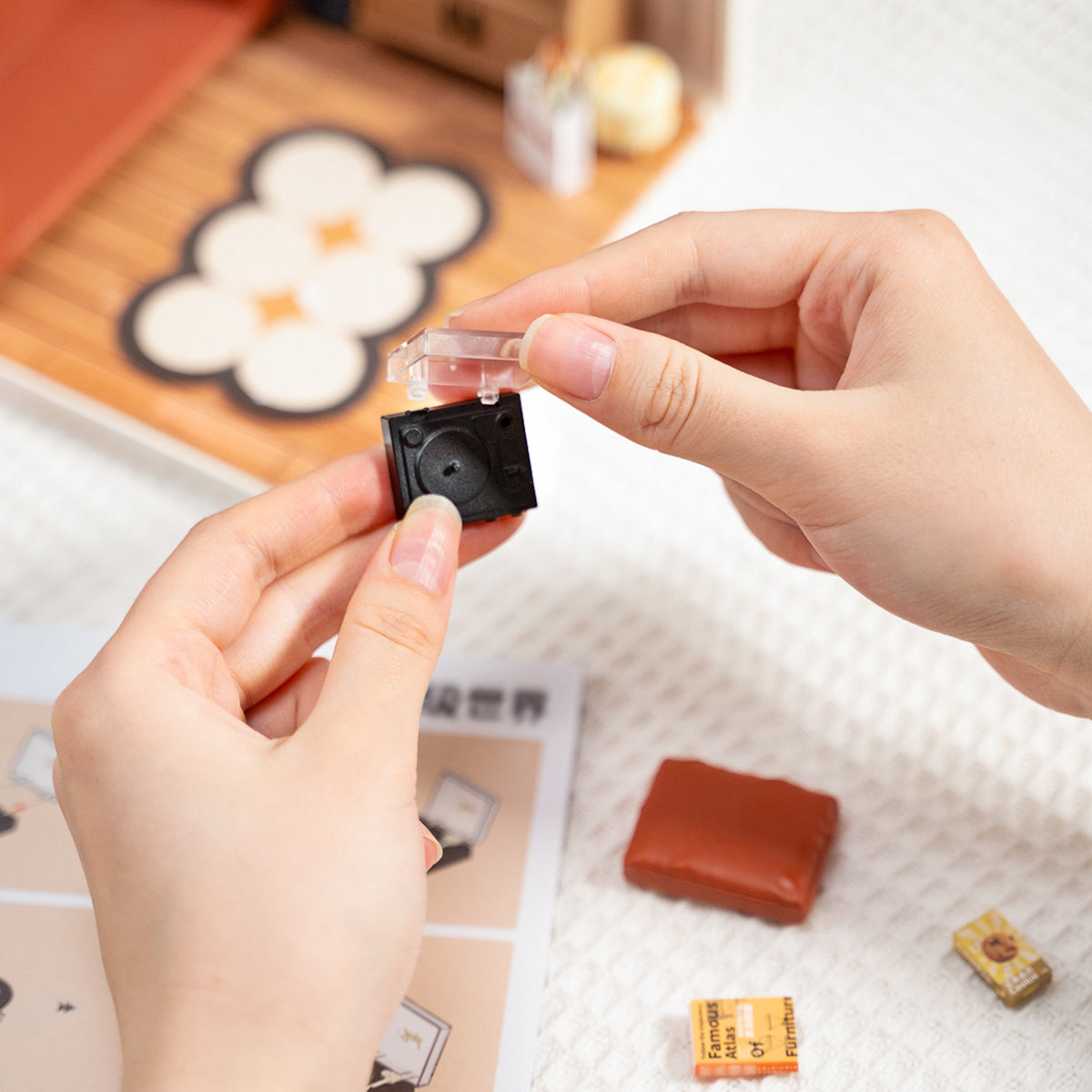 Hände halten ein Miniaturmodell eines Plattenspielers mit geöffnetem Deckel