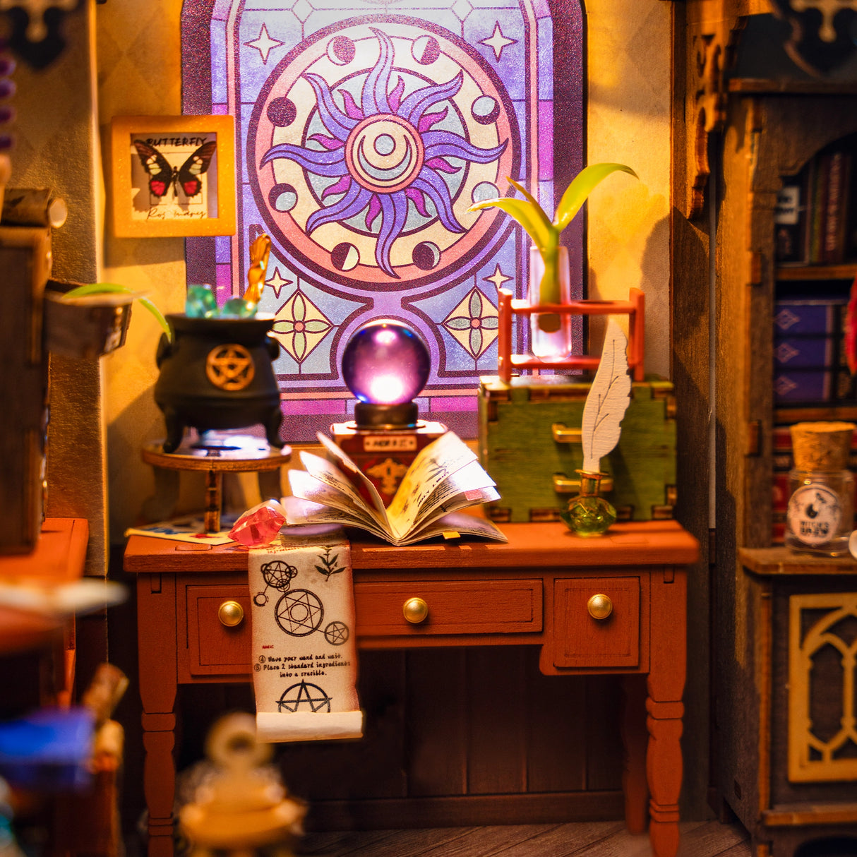 Ein Miniatur-Hexenarbeitszimmer mit einem Schreibtisch, Zauberbuch, Kessel und einem bunten Fenster