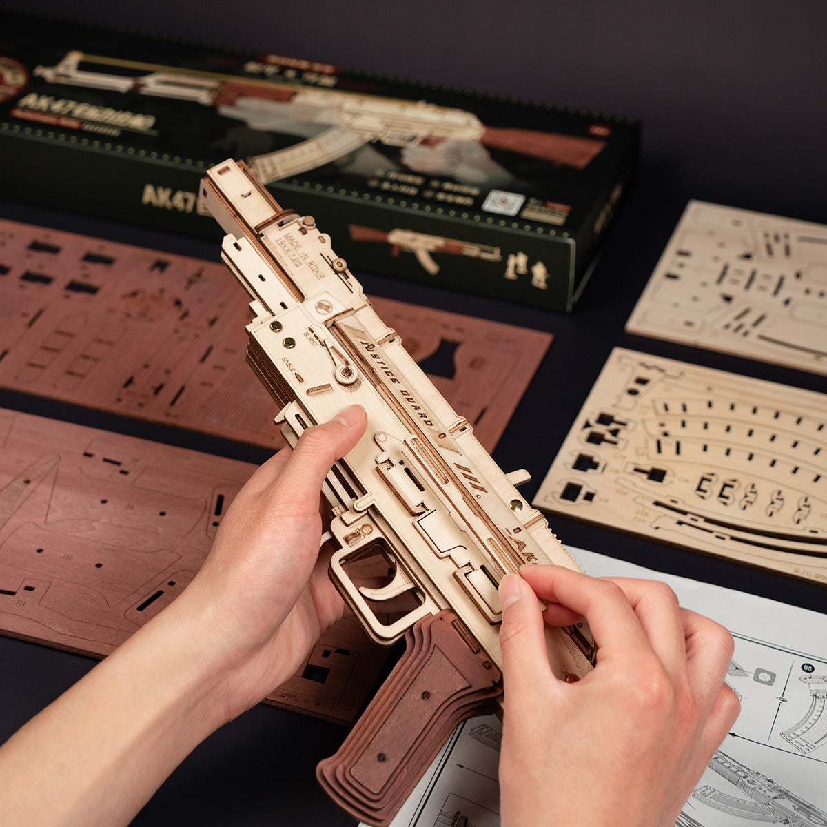 Hände beim Zusammenbau eines hölzernen Modellbausatzes einer AK47