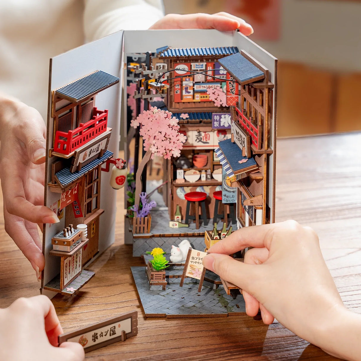 Hände bauen ein japanisches Miniatur-Diorama mit Kirschblüten und Geschäften