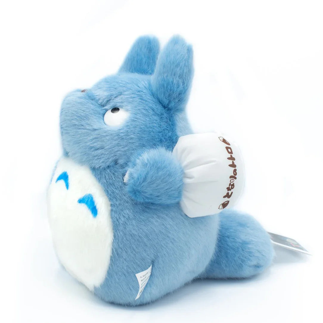 Blaues Plüschtier Totoro mit weißem Beutel vor weißem Hintergrund