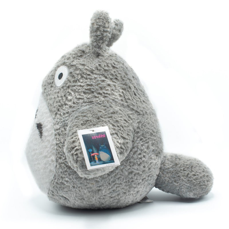 Graues Totoro Plüschtier mit Etikett vor weißem Hintergrund