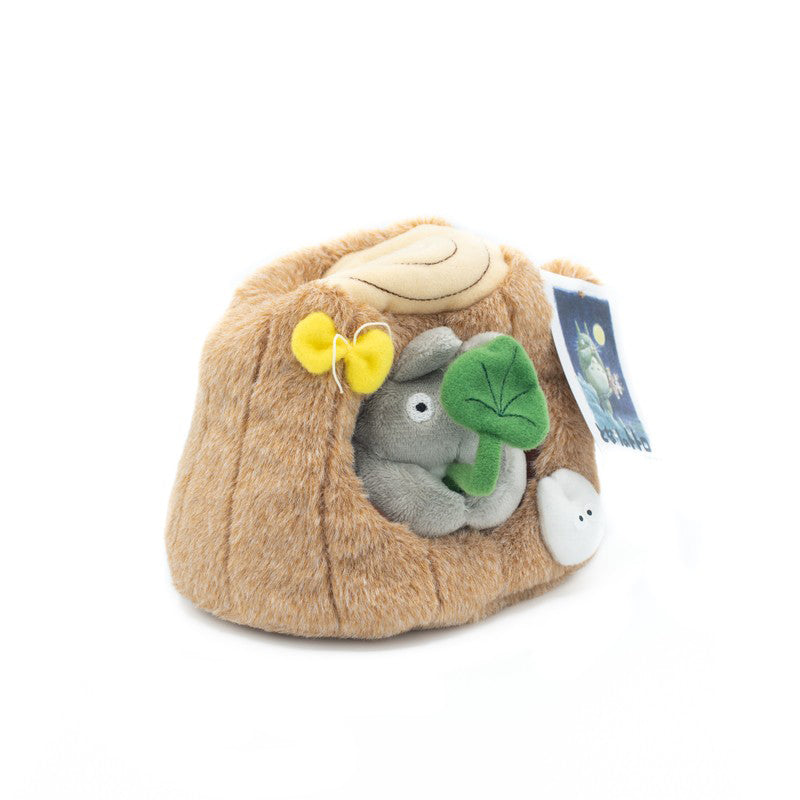 Plüschfigur von Totoro in einem Baumstumpf mit grünem Blatt