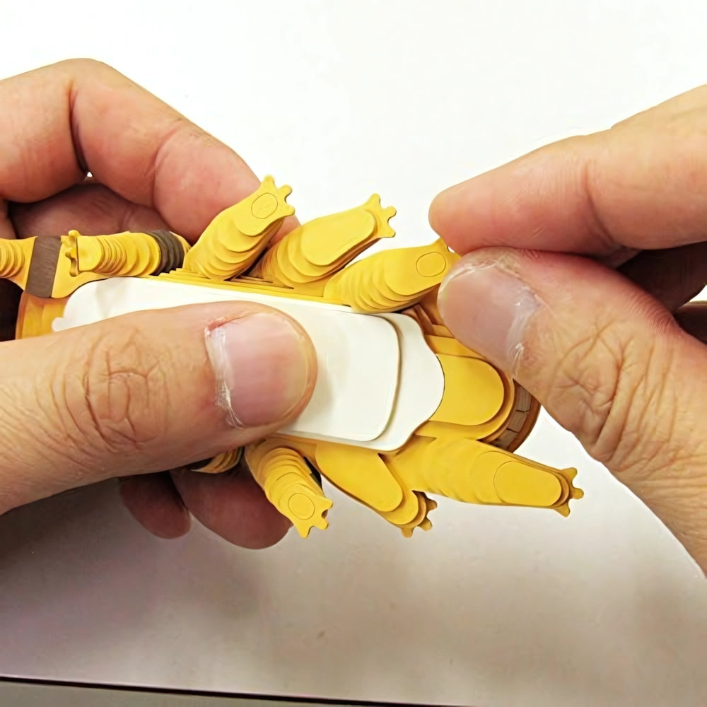 Hände befestigen gelbe Papierfüße an einem weißen Papierkörper