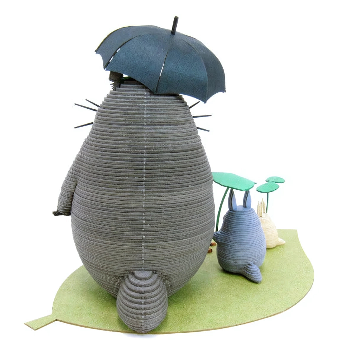 Totoro-Figur mit Regenschirm und kleineren Figuren auf einem Blatt