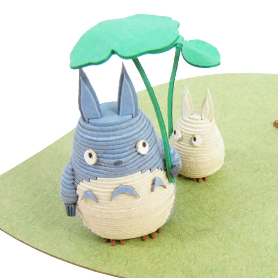 Totoro und kleiner Totoro mit einem Blatt als Regenschirm