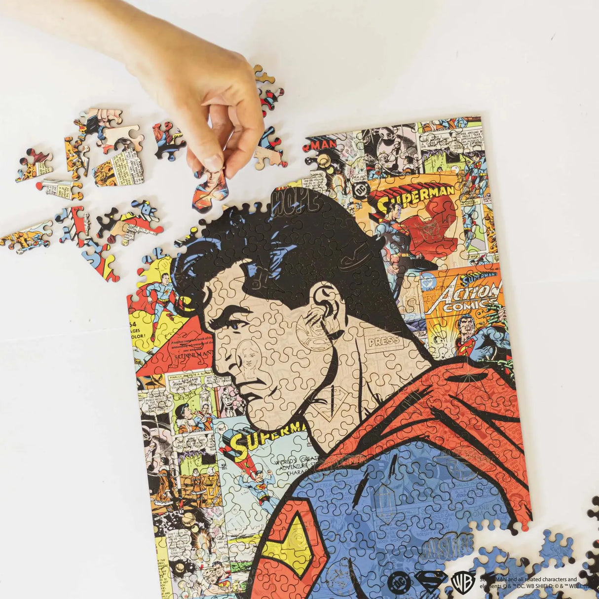 Hand platziert ein Puzzleteil auf einem Superman-Puzzle mit Comic-Panels
