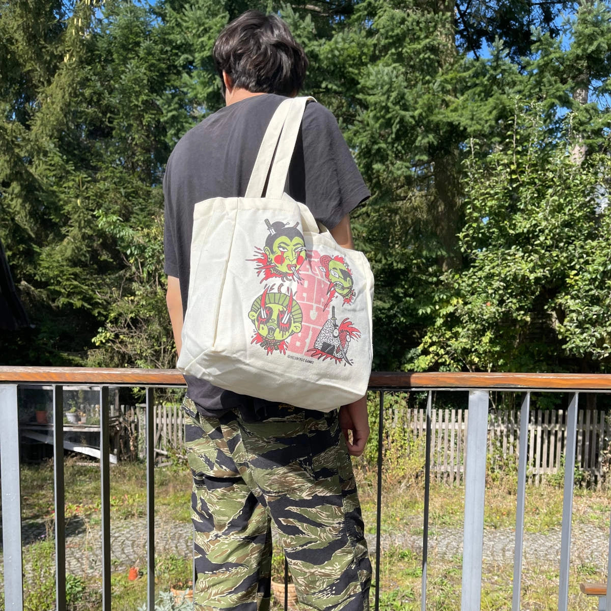 Rückansicht einer Person, die eine weiße Stofftasche mit bunten Comicfiguren trägt