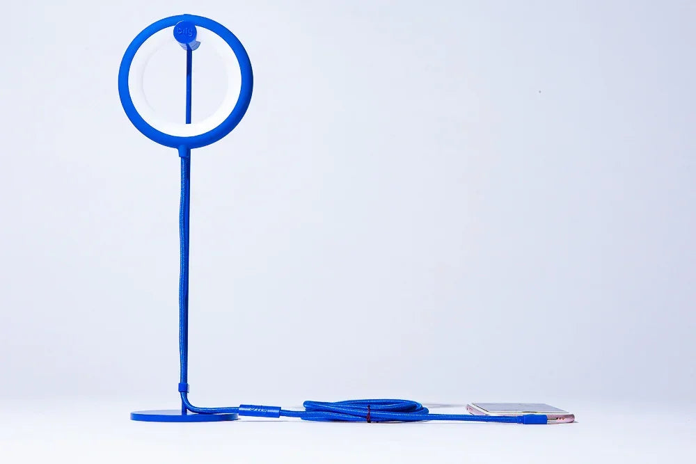 Blaue Ringlampe mit Standfuß und langem Kabel auf weißem Hintergrund