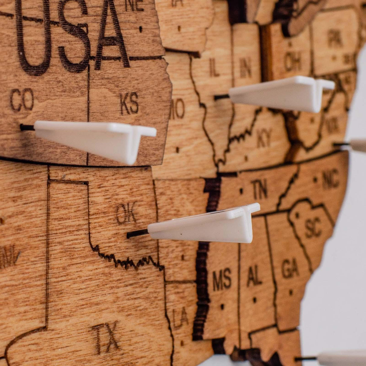 Holzkarte der USA mit eingesteckten weissen Markierungsstiften in verschiedenen Bundesstaaten