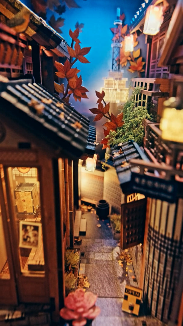 Miniaturmodell einer japanischen Gasse mit beleuchteten Häusern und herbstlichen Ahornblättern