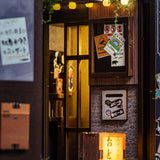 Miniaturmodell eines japanischen Ladeneingangs mit beleuchtetem Fenster und Schildern an der Wand