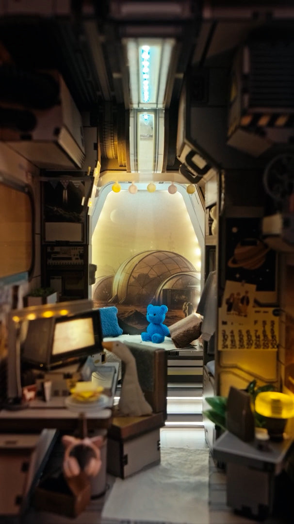 Miniaturmodell eines futuristischen Raumschiffinnenraums mit blauem Teddybär vor einem Fenster mit Marslandschaft