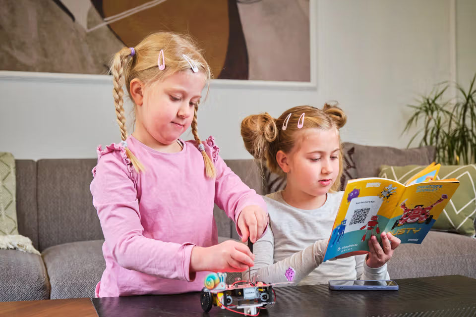 Zwei Mädchen bauen die CircuitMess Dusty Roboterkrabbe gemeinsam anhand der Bauanleitung zusammen