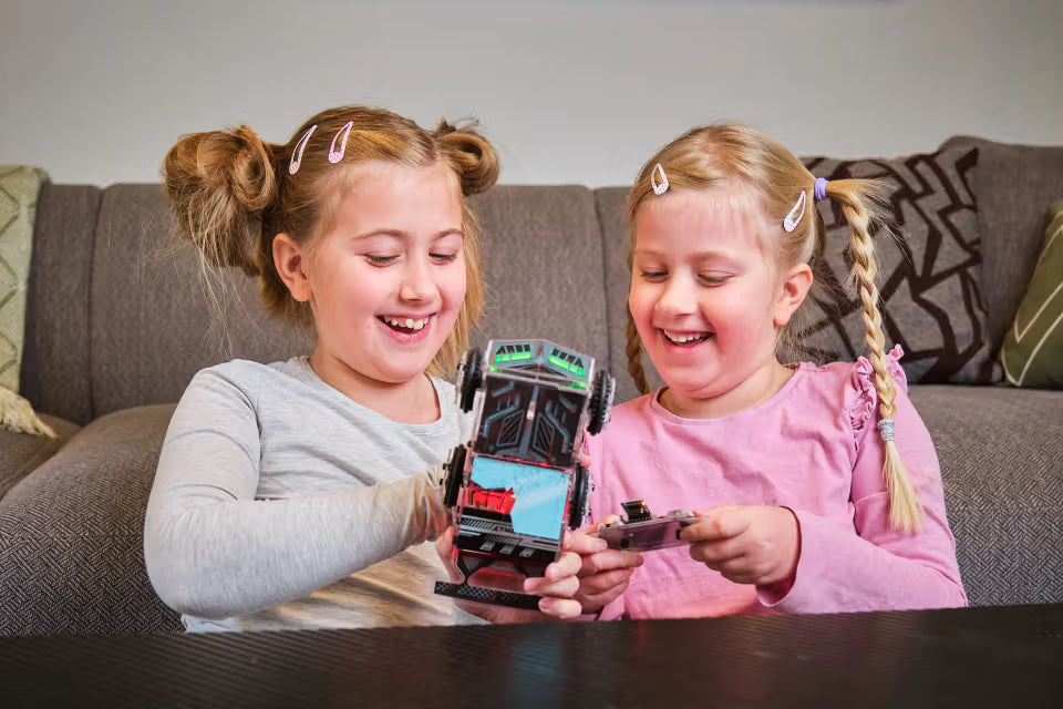 Zwei Kinder betrachten gemeinsam das fertig gebaute CircuitMess Sparkly Roboterauto